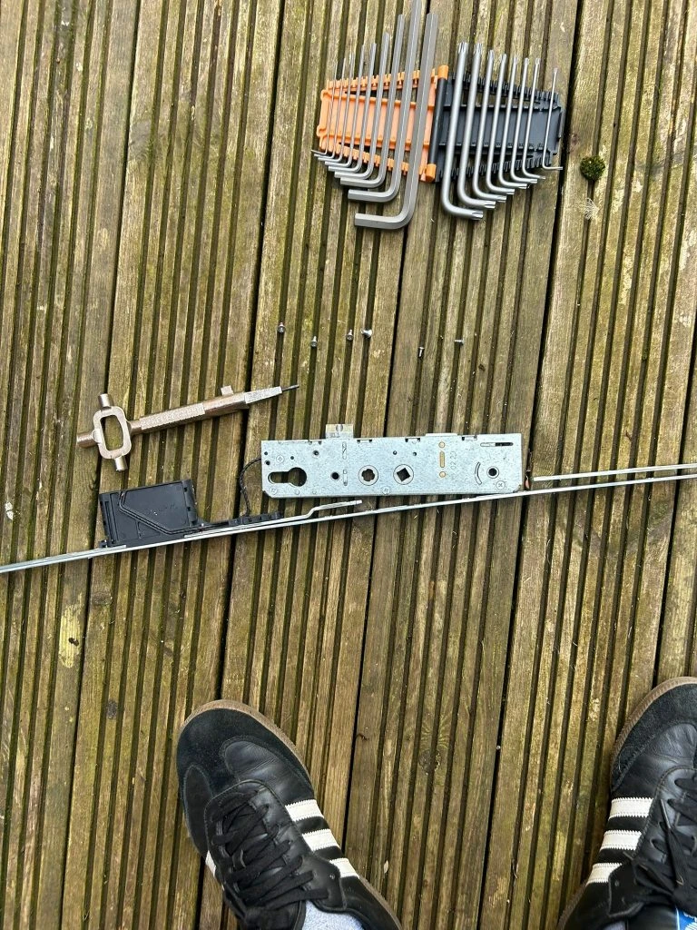 Lock mechanism and tools laid out on wooden decking during repair work